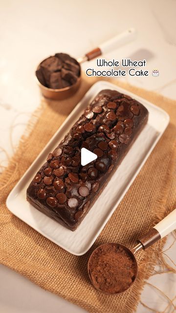 a white plate topped with chocolate cake next to two spoons