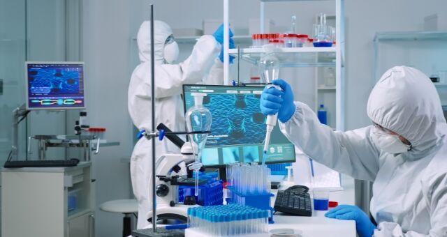 two people in white lab coats are doing something with blue liquid and flasks