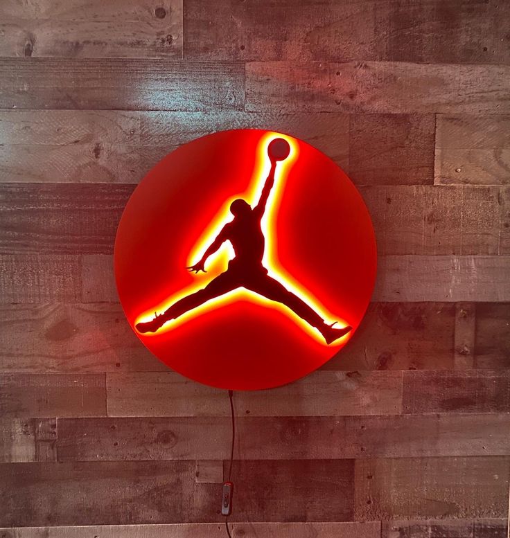 a neon sign with a basketball player on it's side hanging from the wall