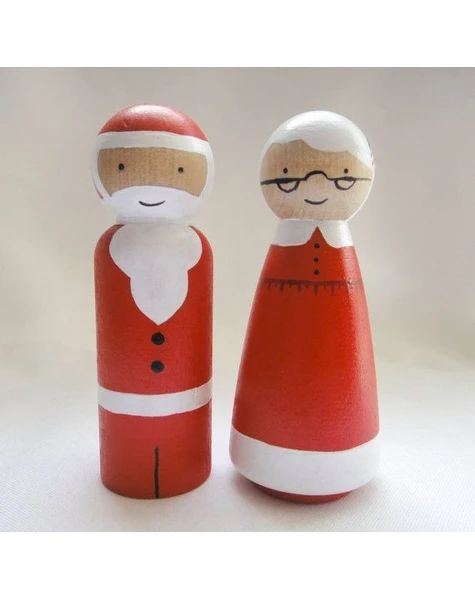 two wooden dolls are dressed as santa and mrs claus, one is red with white trim