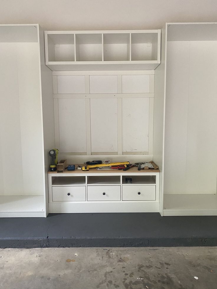 an empty room with built in cabinets and drawers on the wall, including a bench