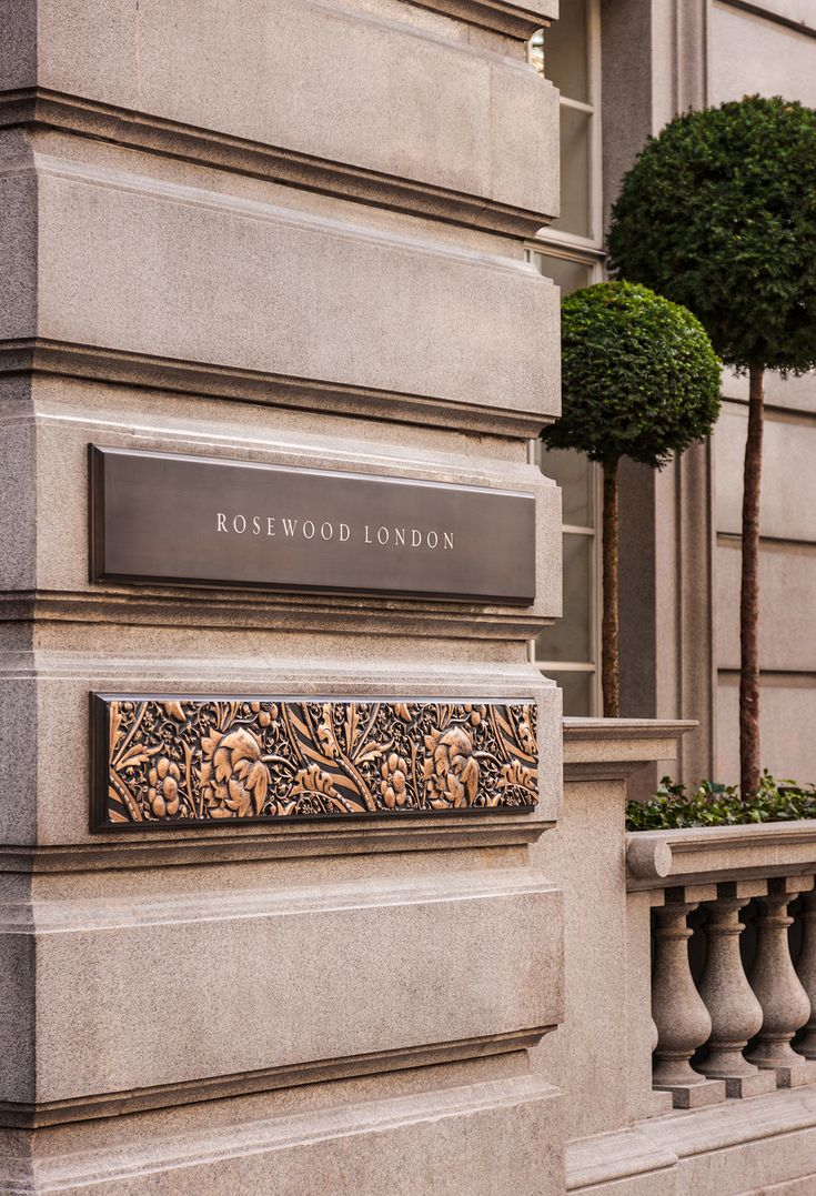 the entrance to rosewood london is shown in front of a tall building with trees on either side