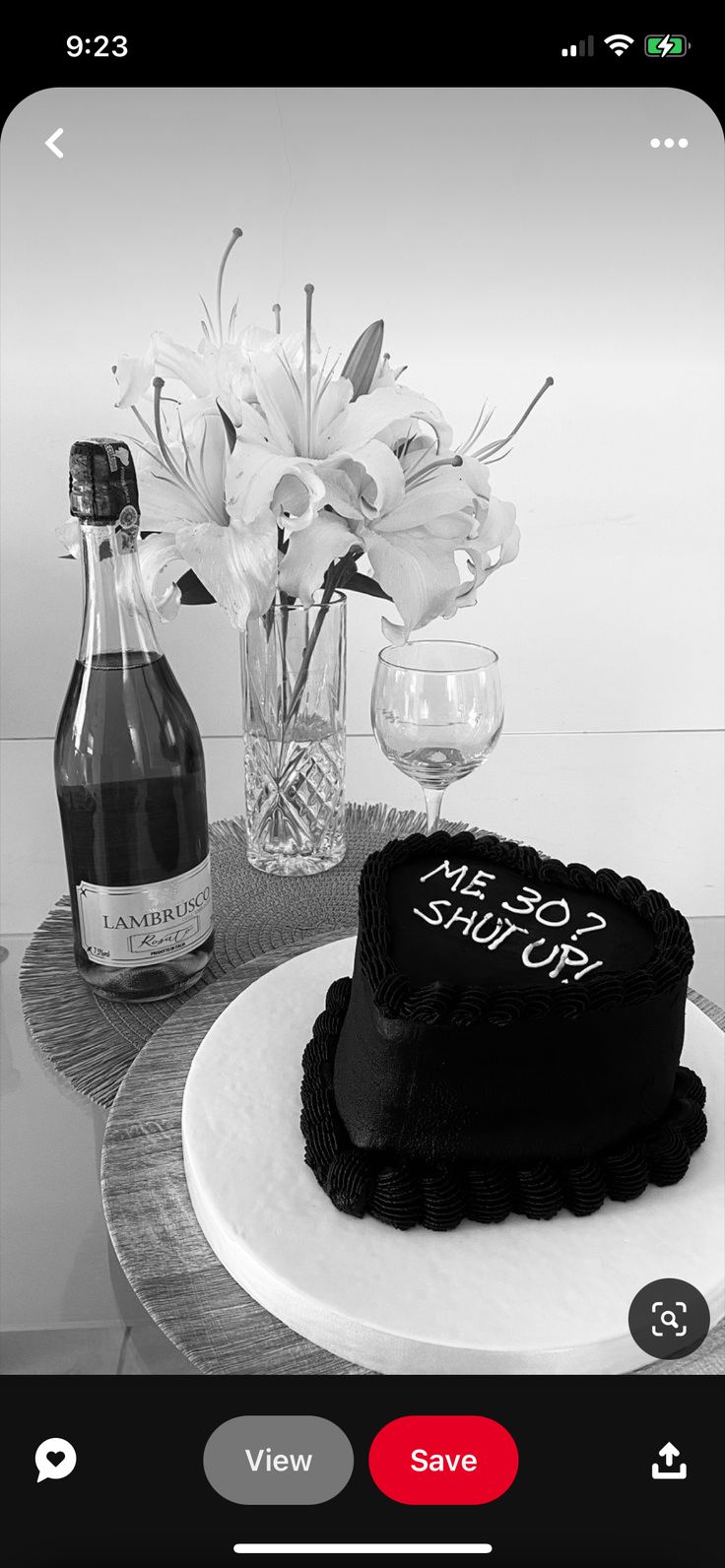 a black and white photo of a cake on a table next to a bottle of wine