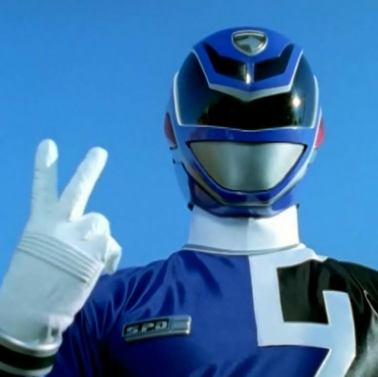 a man in a blue and white suit making the peace sign with his hand while wearing a helmet