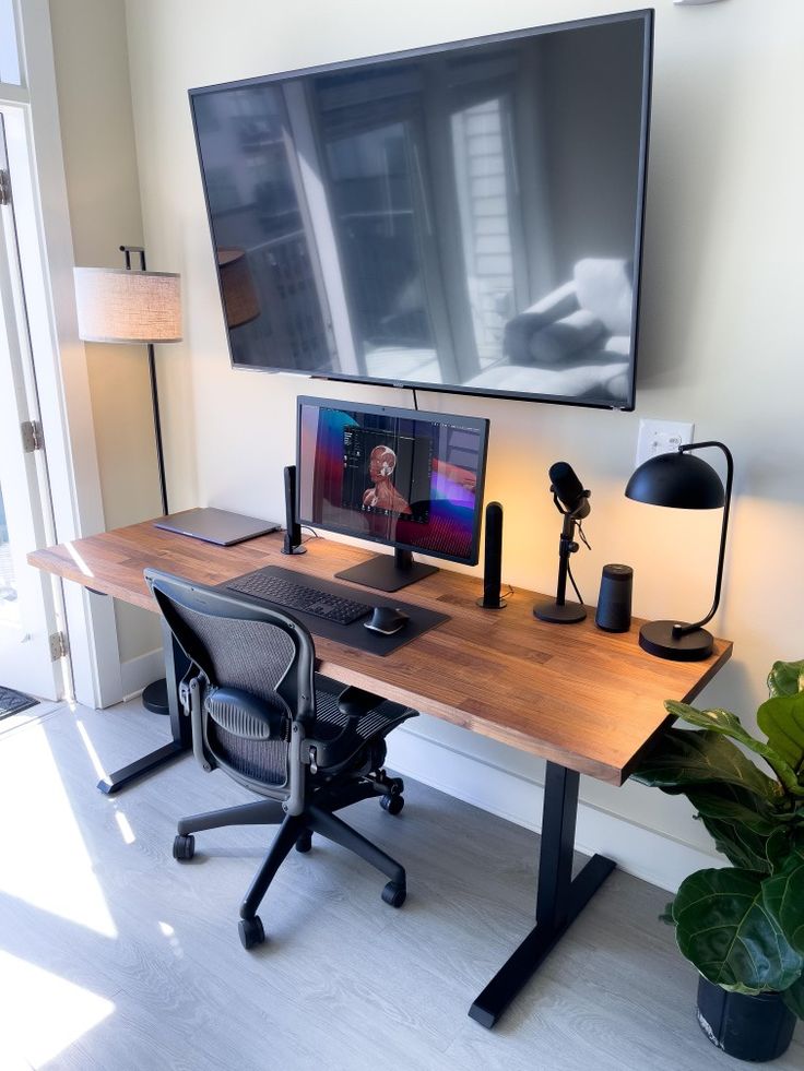 a desk with a monitor, keyboard and mouse on it in front of a large screen