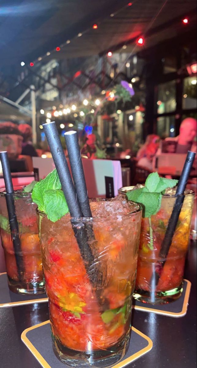 three glasses filled with drinks sitting on top of a table