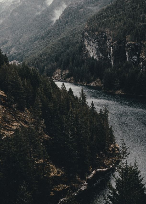 a river surrounded by mountains and trees in the middle of it's own area