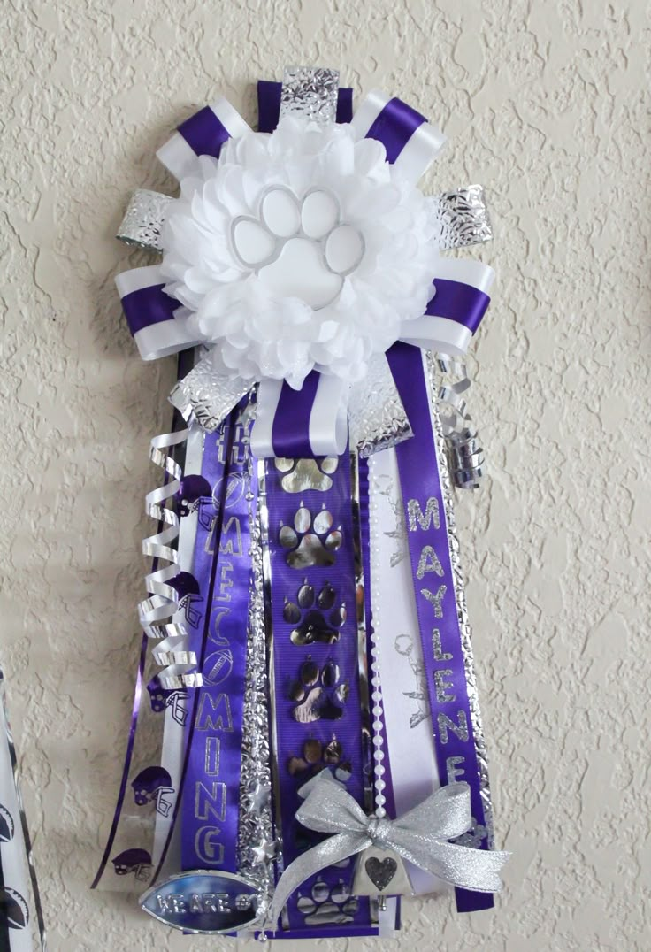 a purple and white ribbon decoration hanging on the wall