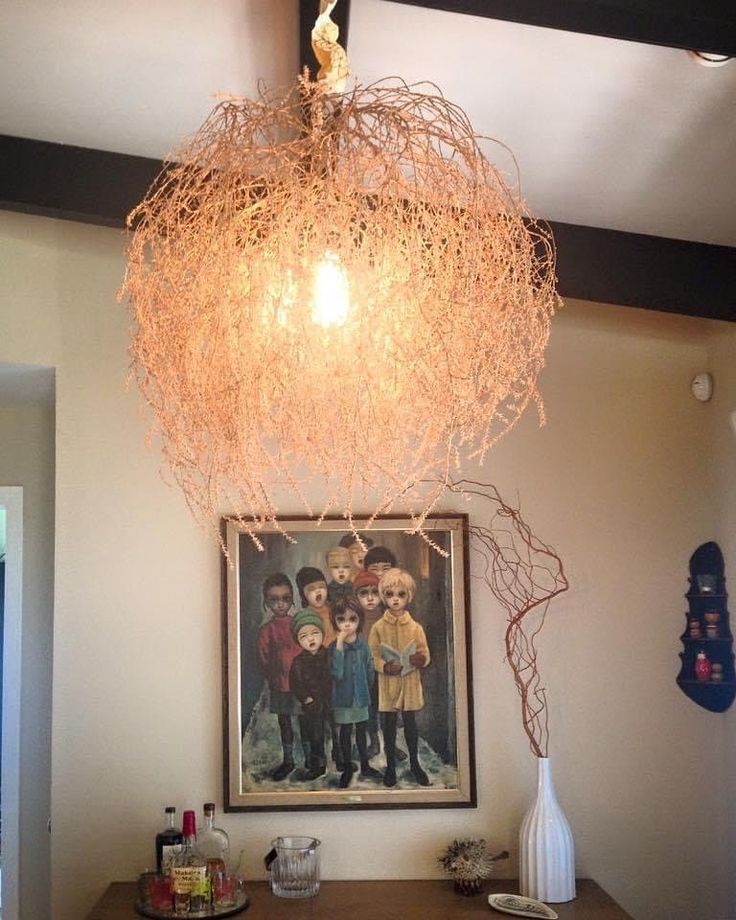 a dining room table with a painting on the wall and a hanging light fixture above it