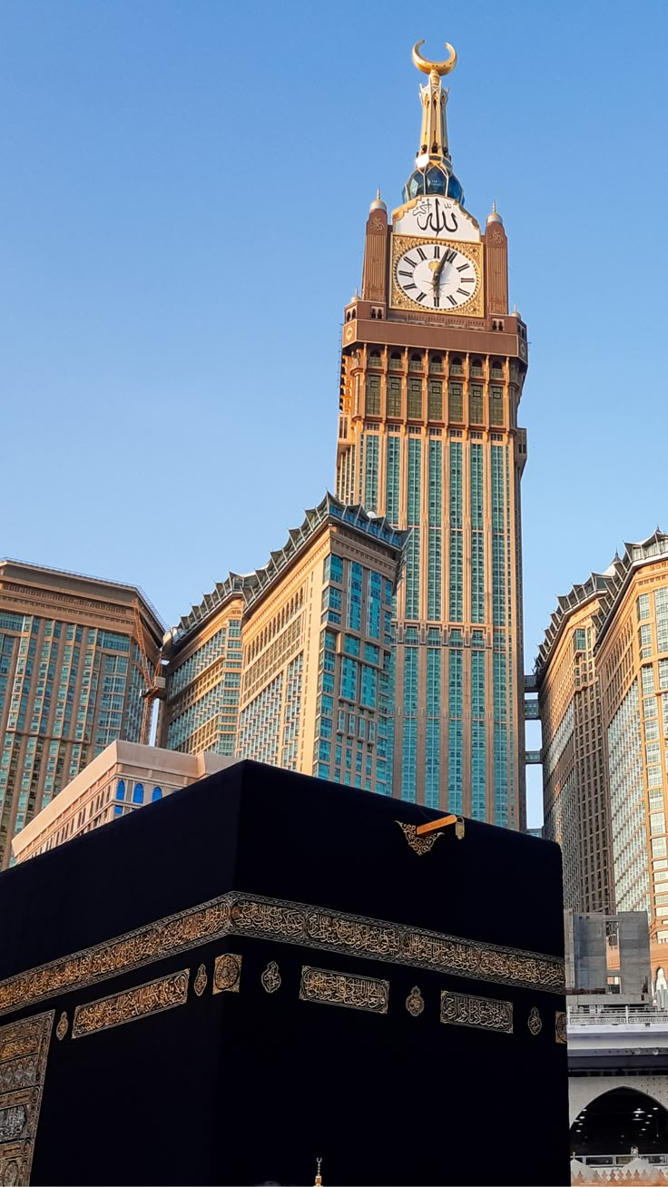 a large black box in front of a tall building with a clock on it's face