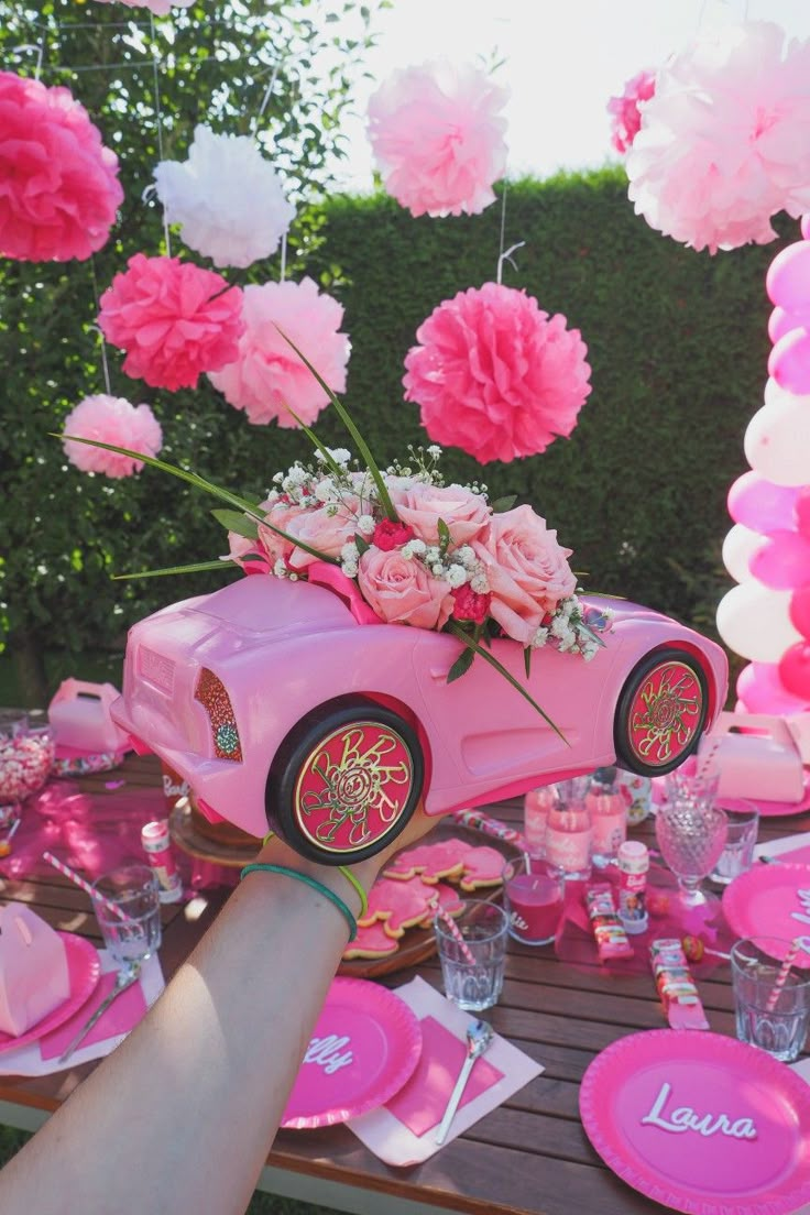 a pink car with flowers on it is sitting in the middle of a party table