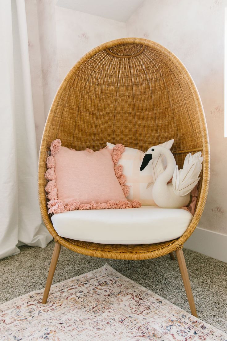 a wicker chair with pillows on it in front of a window