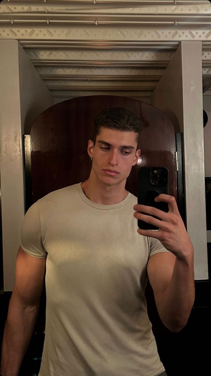 a young man taking a selfie in front of a mirror with his cell phone