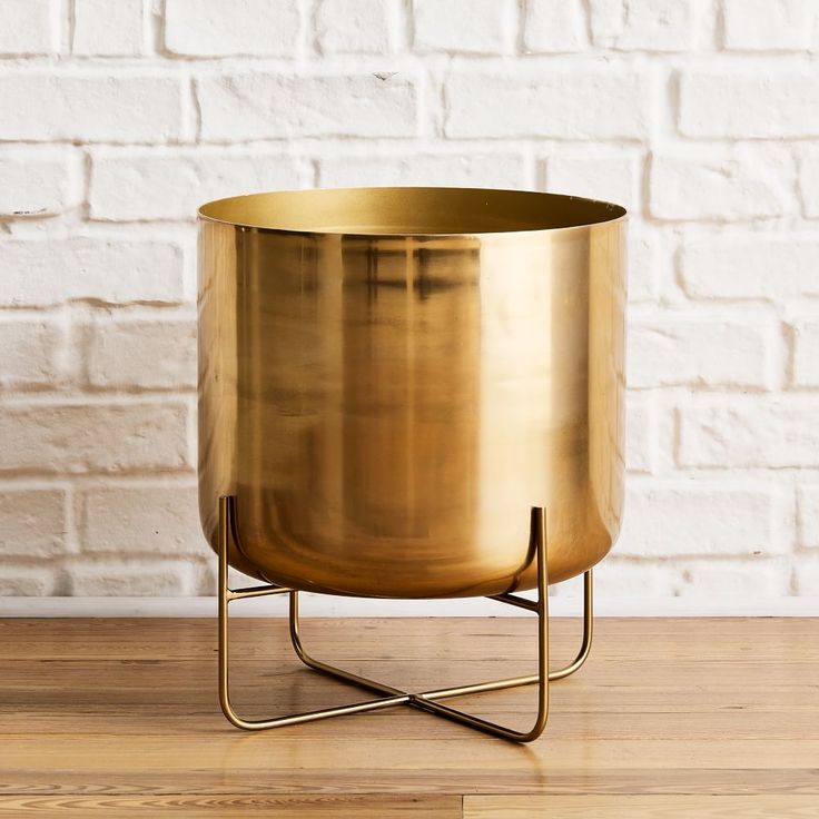 a large metal pot sitting on top of a wooden table next to a white brick wall