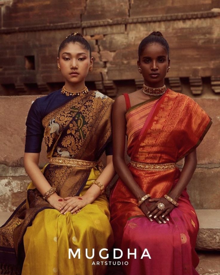 two young women sitting next to each other in colorful outfits and jewelry on their heads