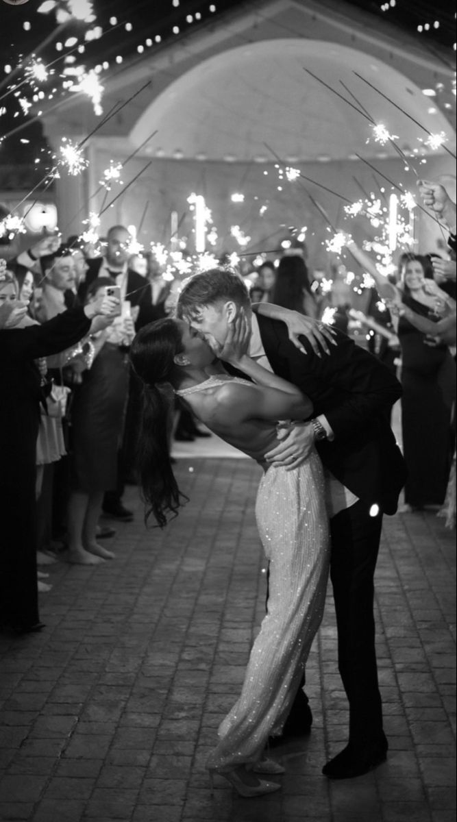 a bride and groom kissing in front of sparklers at their wedding reception on the dance floor