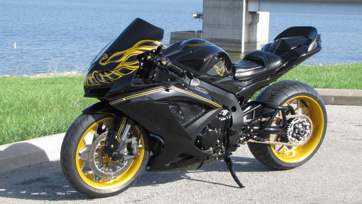 a black and yellow motorcycle parked next to the water