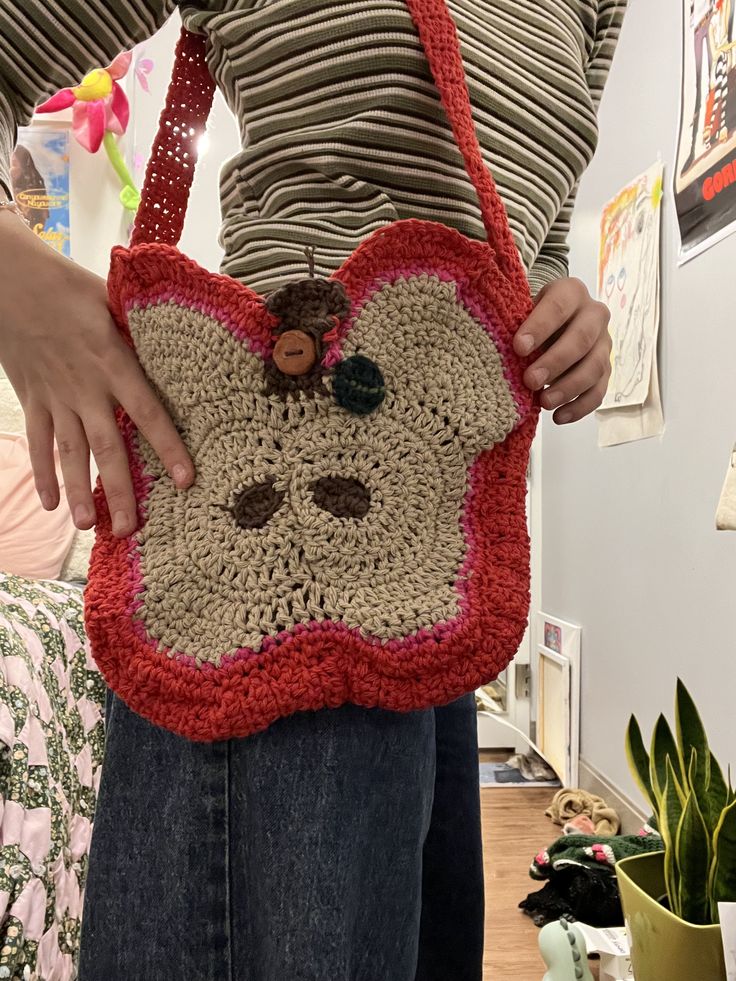 a woman is holding a crocheted purse with a monkey face on the front