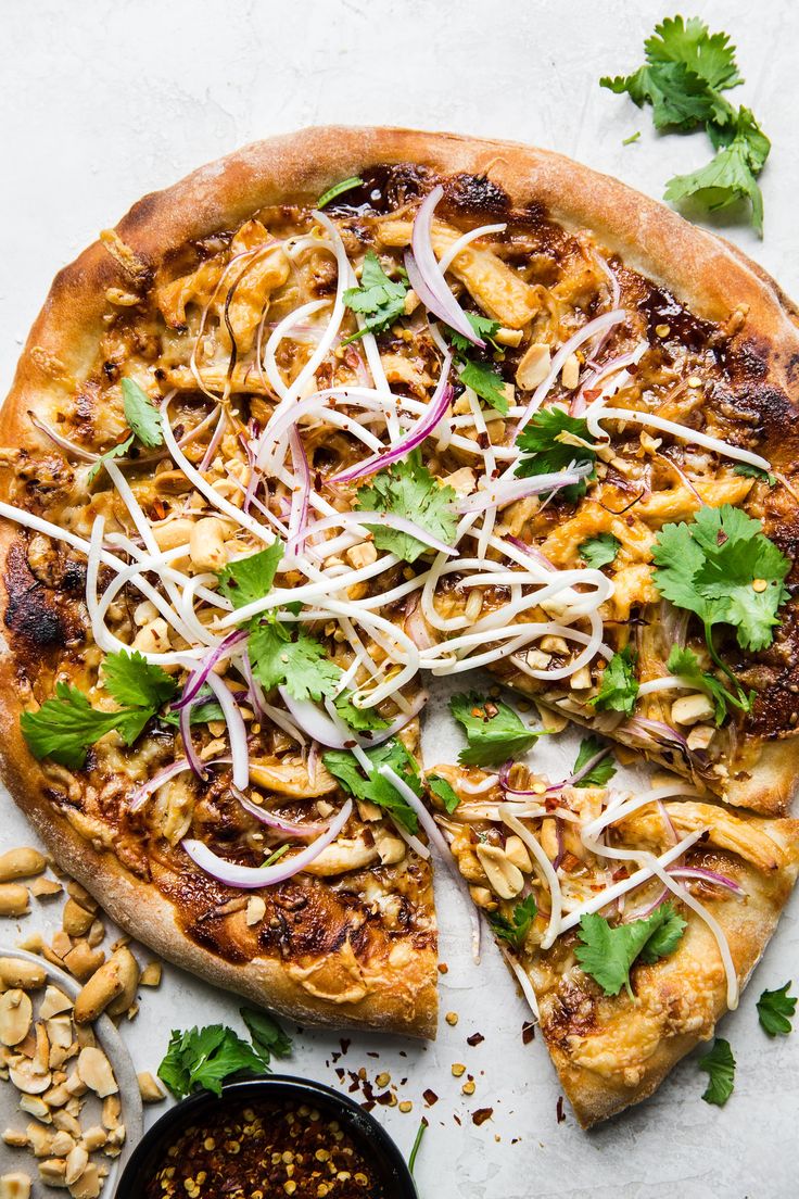 a pizza sitting on top of a pan covered in toppings next to a bowl of sauce