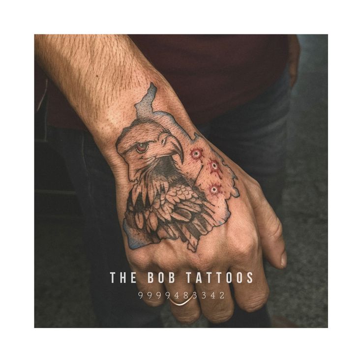 a man's hand with an eagle and flowers tattoo on his left wrist,