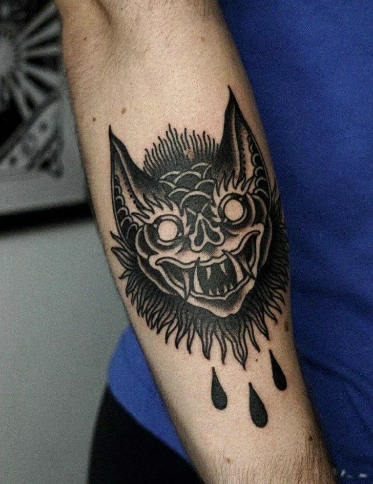 a man with a tattoo on his arm that has a demon face and rain drops