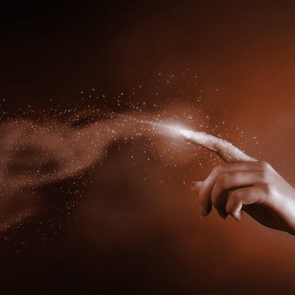 a woman's hand reaching out to touch the dust on her fingers, against a dark background