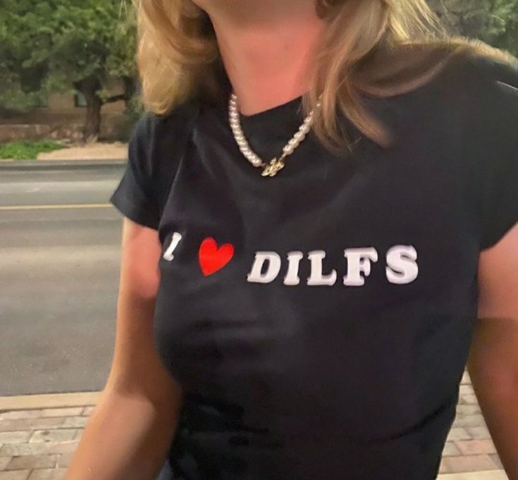 a woman wearing a black shirt that says i love dilfs on it with a red heart