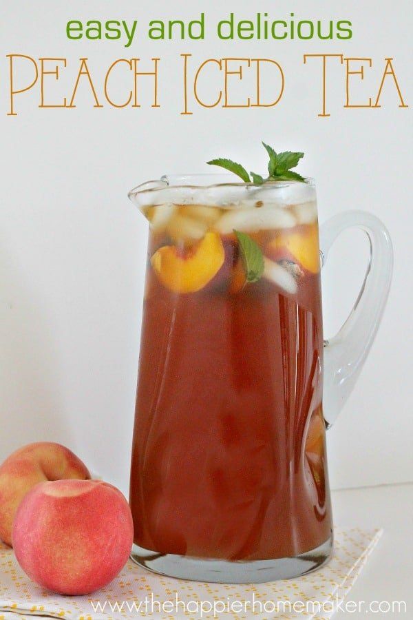 a pitcher filled with peach iced tea next to an apple