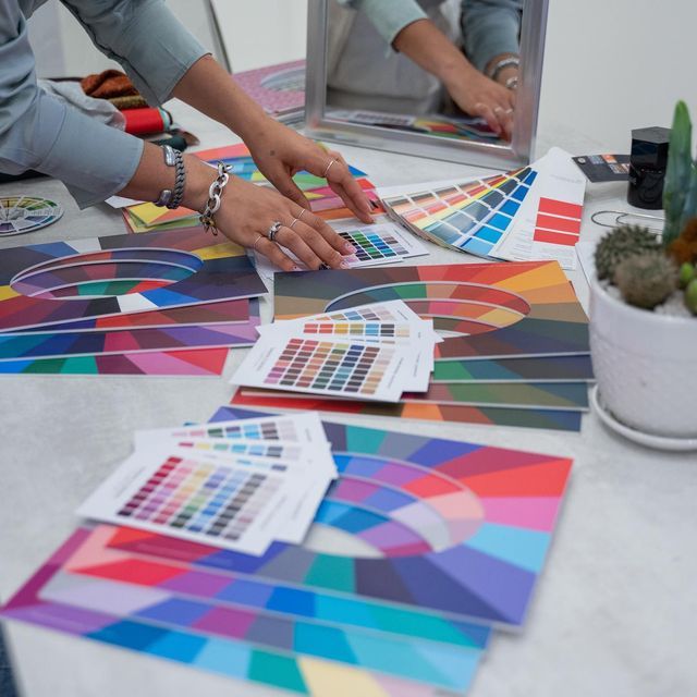 two people are working on some art work with color samples and paintbrushes in front of them