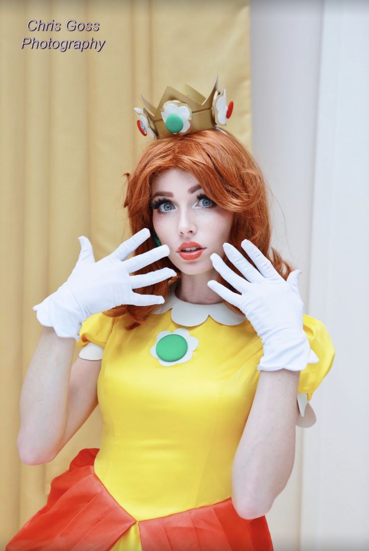 a woman in a yellow dress and white gloves posing for the camera with her hands on her face