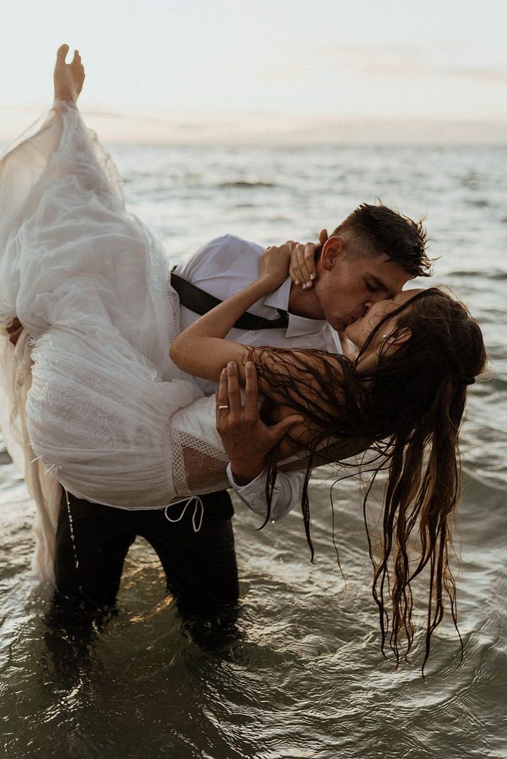 a man and woman are kissing in the water while holding on to each other's shoulders