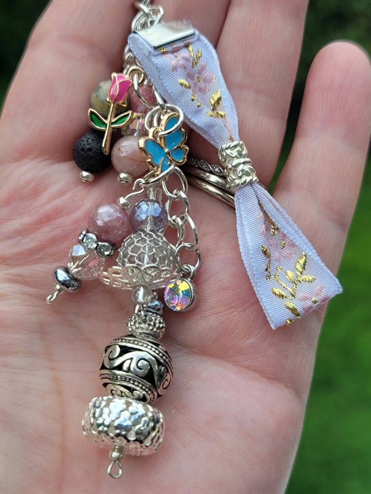 a hand holding a bunch of charms in it's palm with a ribbon around it