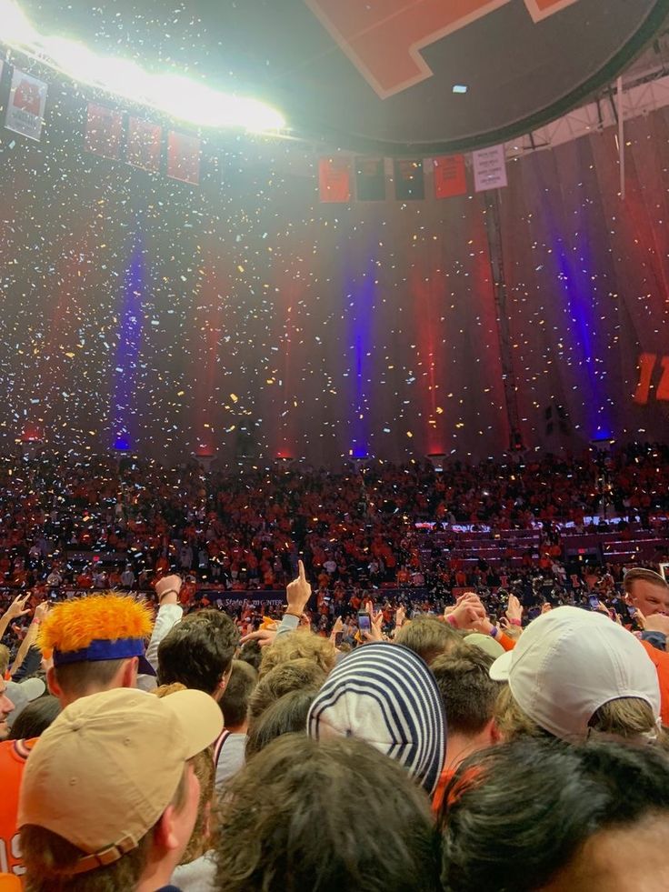 a large crowd at a basketball game with confetti thrown in the air