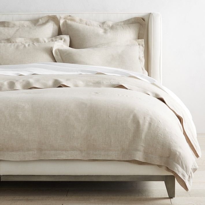 a bed with white linens and pillows in a minimalistic bedroom setting on a hard wood floor