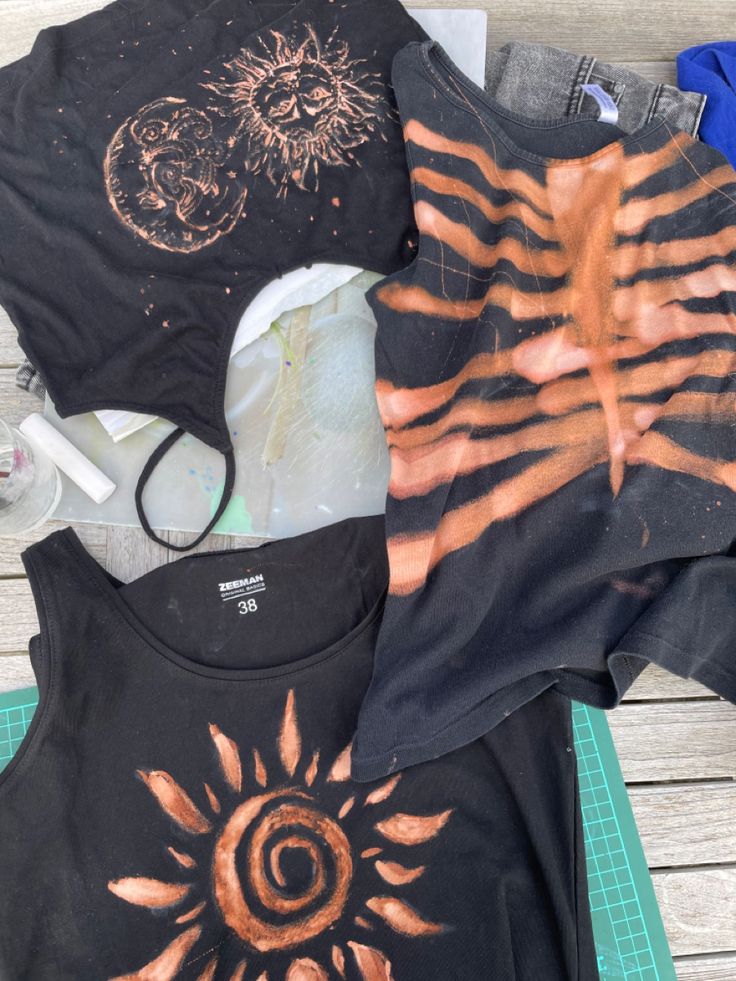 several t - shirts are sitting on a table with scissors and other items around them