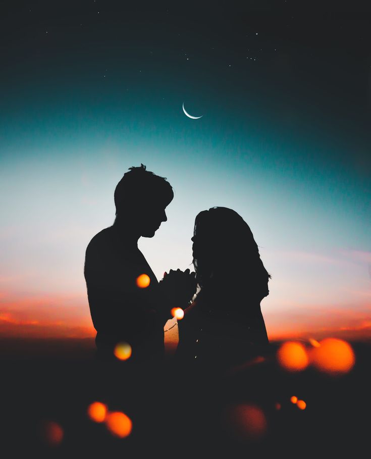 two people standing next to each other in the dark at night with bright lights on them