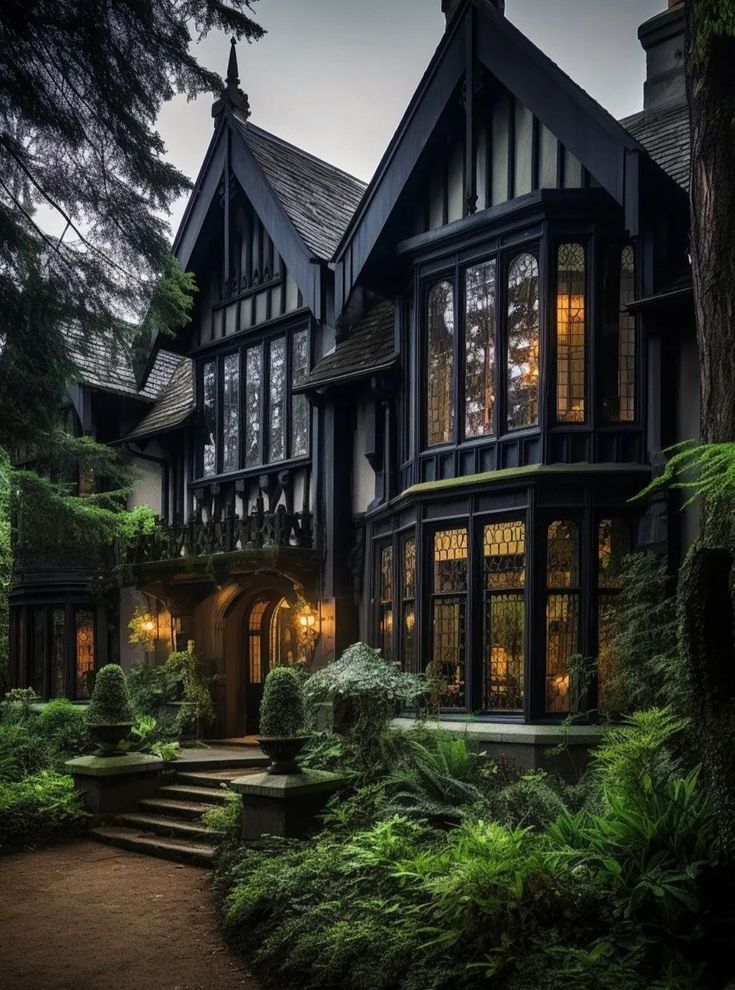 a large house with lots of windows and plants in the front yard at night time