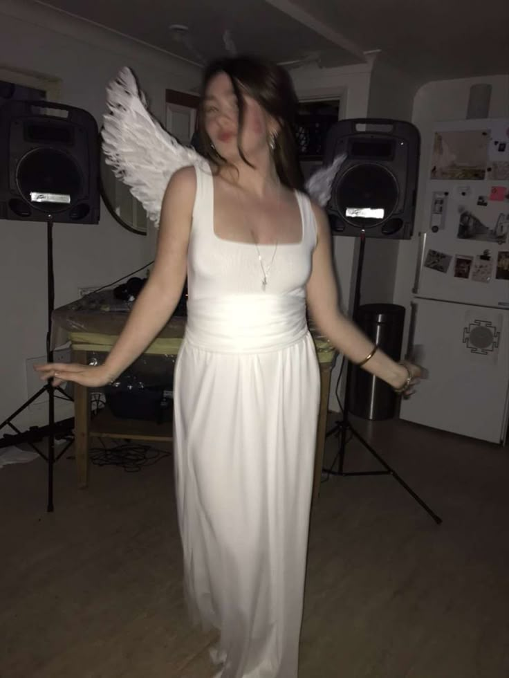 a woman in a white dress with angel wings on her shoulders and arms spread out