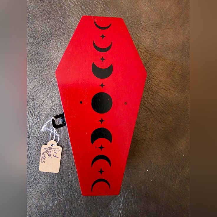 a red box with black phases on it and a tag hanging from the front side