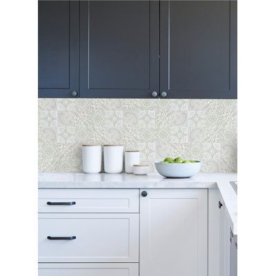 a bowl of fruit is sitting on the counter in this white and blue kitchen with black cabinets