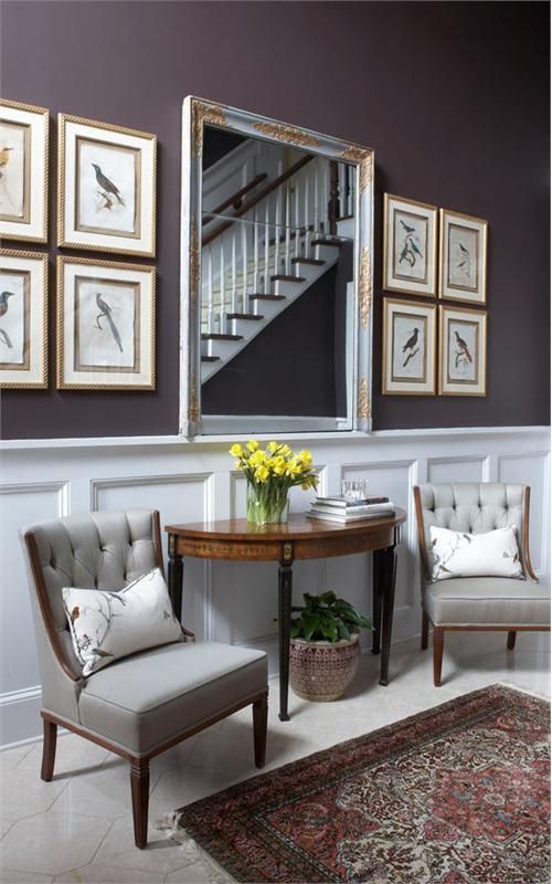 a living room filled with furniture and framed pictures on the wall next to a table