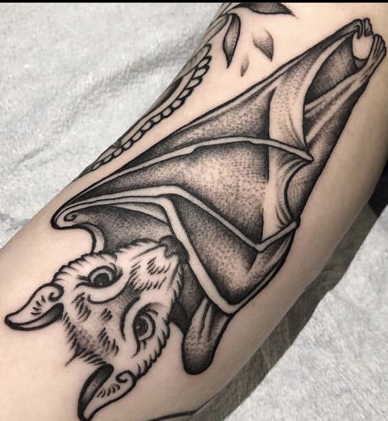 a black and white photo of a tattoo on someone's leg with a bat