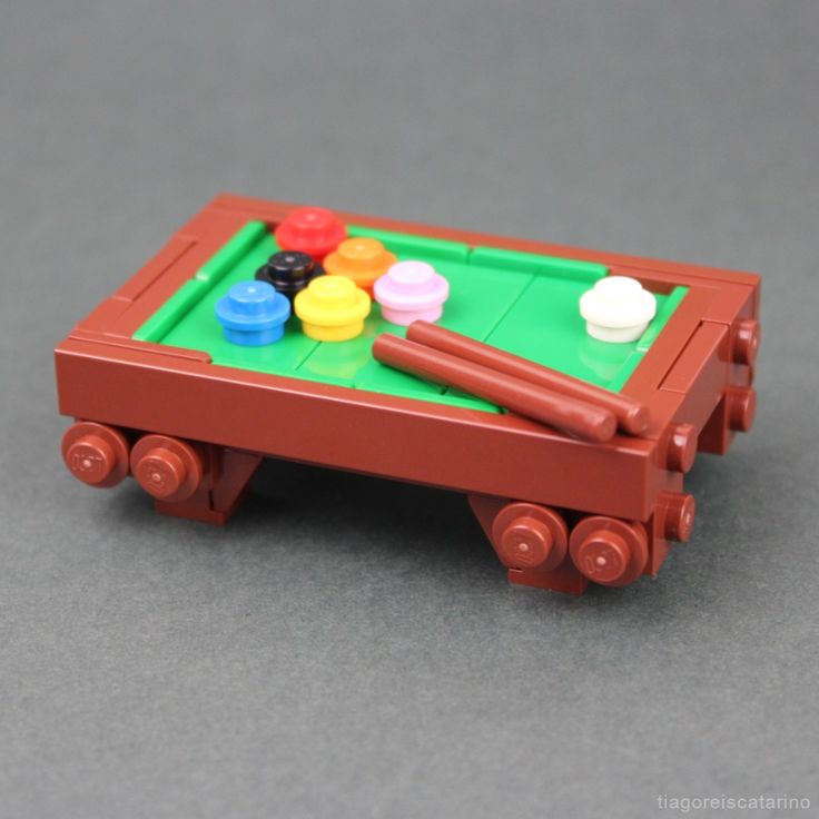 a toy pool table with balls and crayons in it on a gray surface