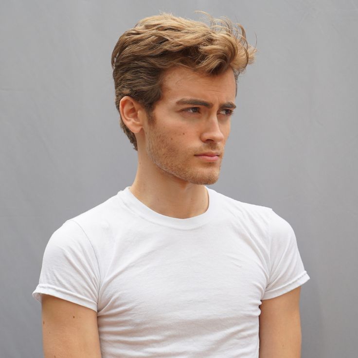 a young man wearing a white t - shirt looking at the camera with a serious look on his face