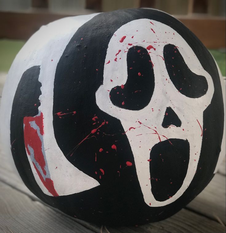 a black and white ball with red paint on it that has a skull painted on it