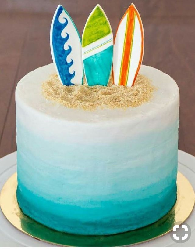 there is a cake that has three surfboards on it and sand in the middle