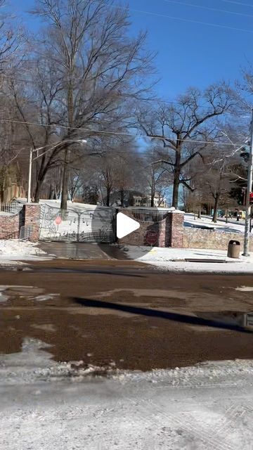 an empty street with snow on the ground and trees in the backgrouds