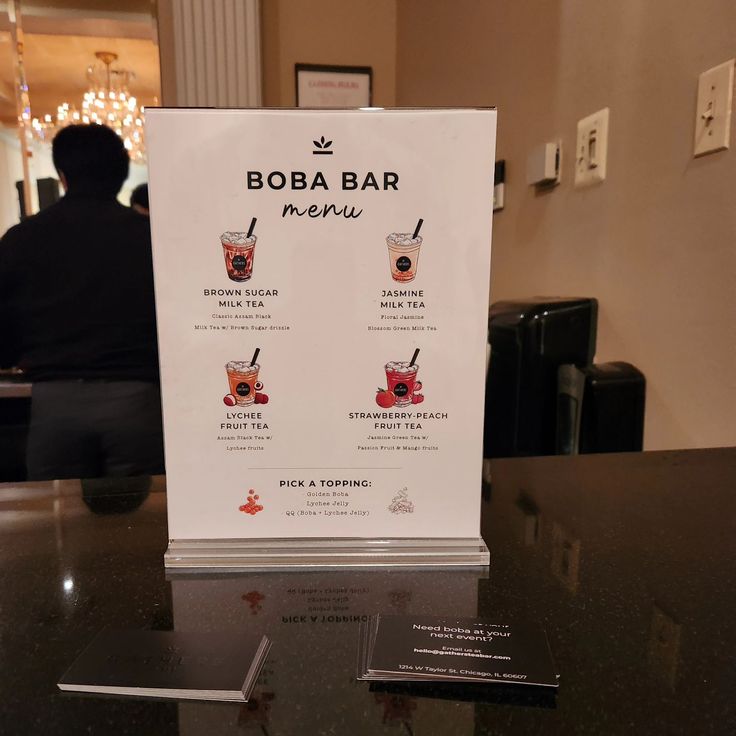 a menu for boba bar is displayed on a table in front of a man