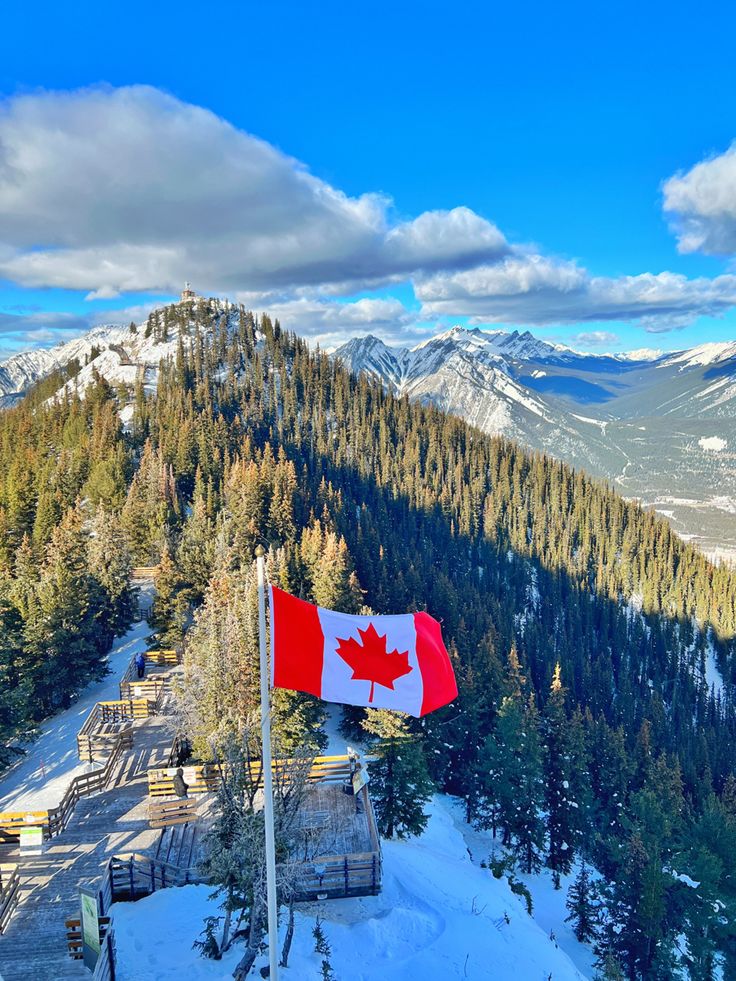 the canadian flag is flying high in the mountains