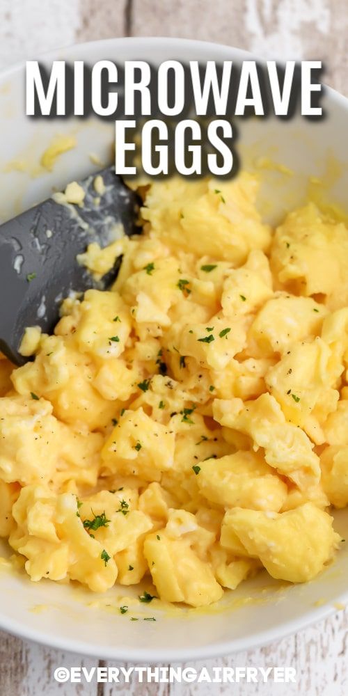 a white bowl filled with scrambled eggs on top of a wooden table